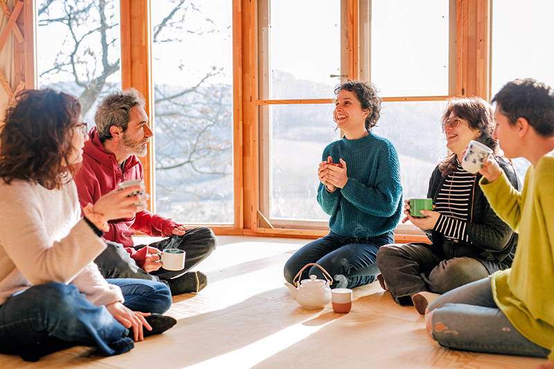 Il team di casa del cuculo seduto in cerchio sul pavimento chiacchiera e beve un tè